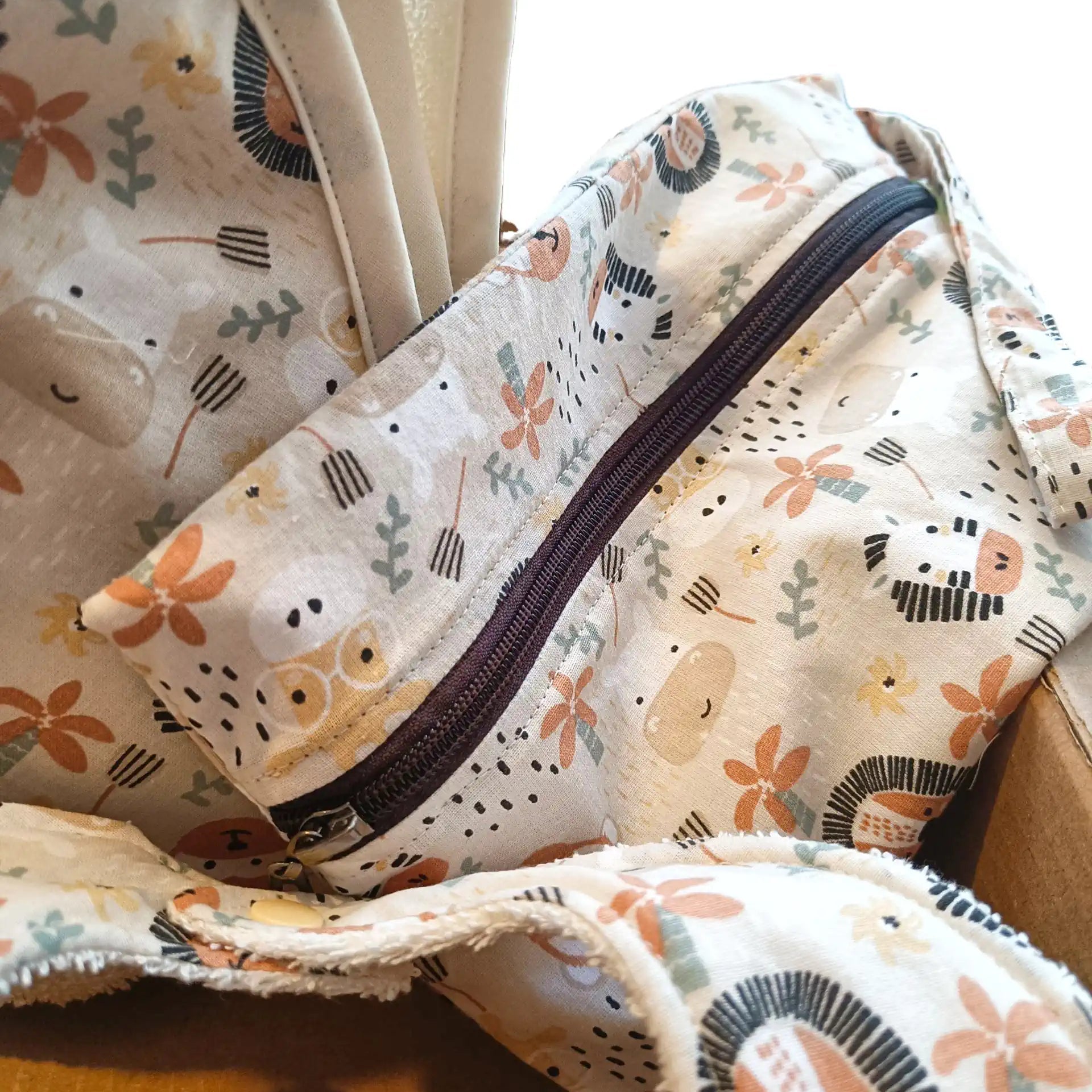 Detalle de la bolsa impermeable con cremallera y estampado de leones, osos y jirafas.