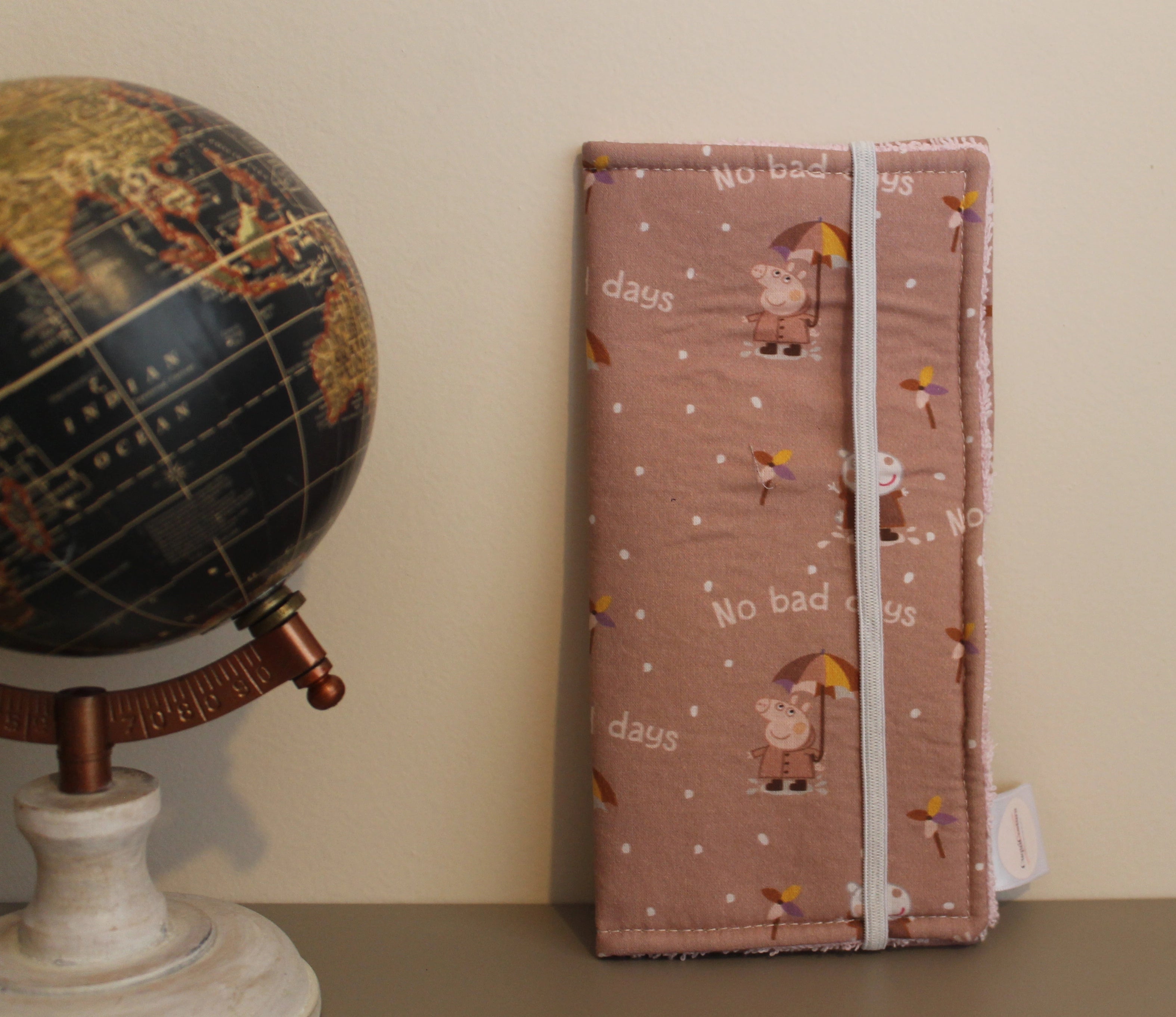 Estuche dental infantil con estampado de Peppa Pig y frase "No bad days", junto a un globo terráqueo sobre fondo beige