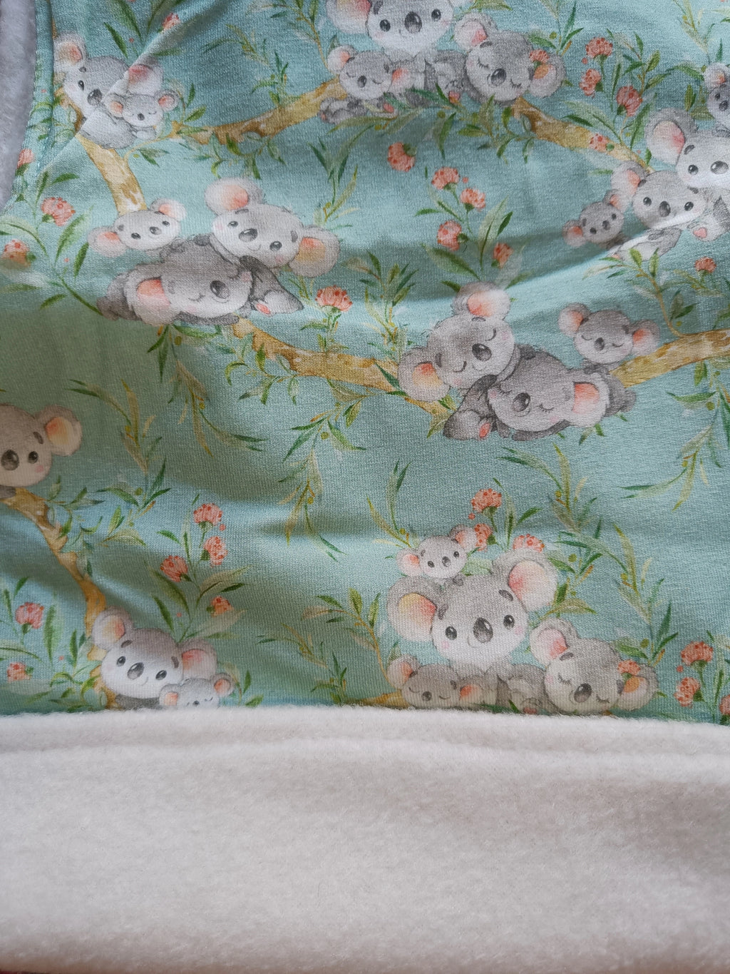 Primer plano del tejido Buff’n’hood “Koalas azul”, mostrando la textura suave del forro blanco y el diseño exterior. [variant: Blanco]