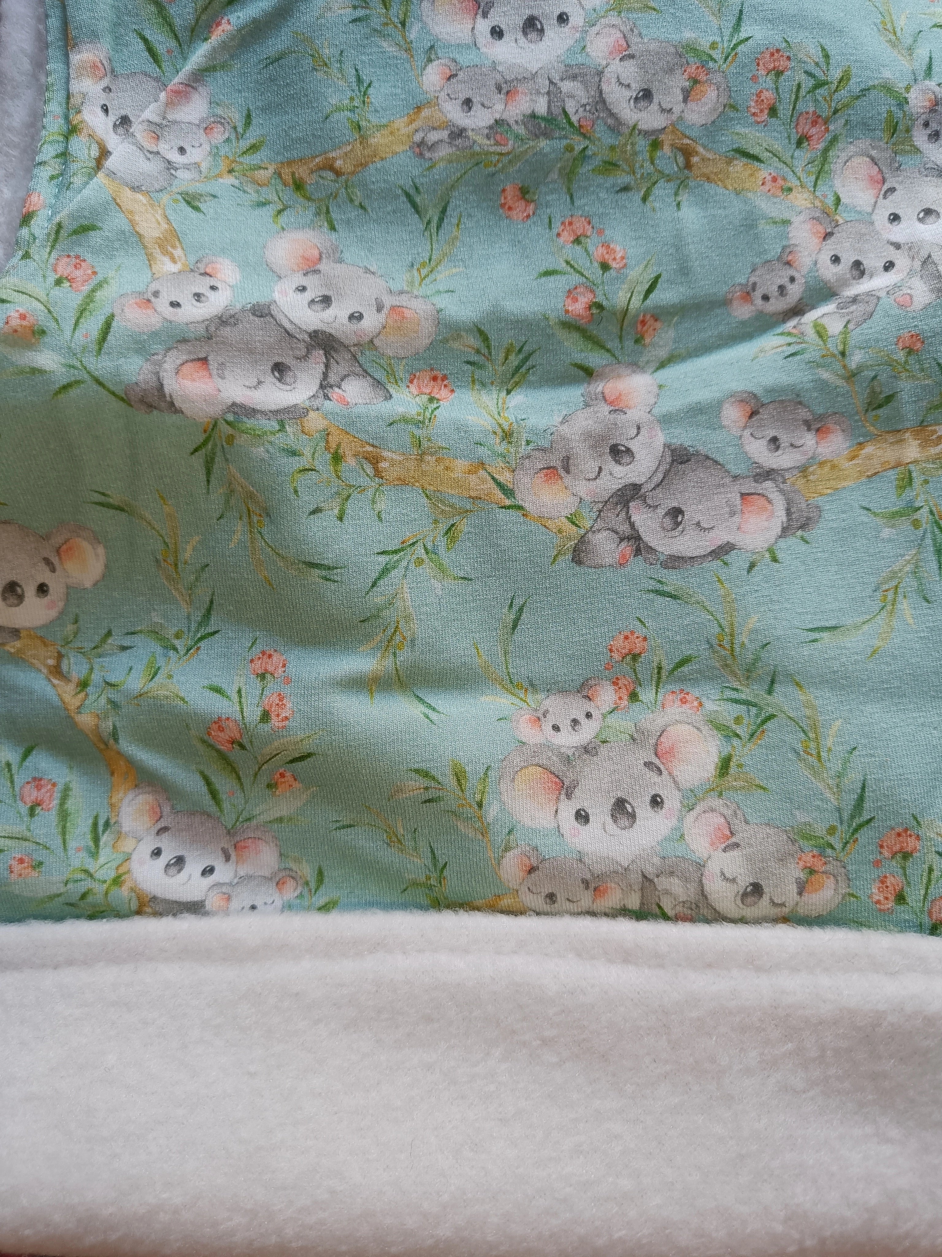 Primer plano del tejido Buff’n’hood “Koalas azul”, mostrando la textura suave del forro blanco y el diseño exterior. [variant: Blanco]