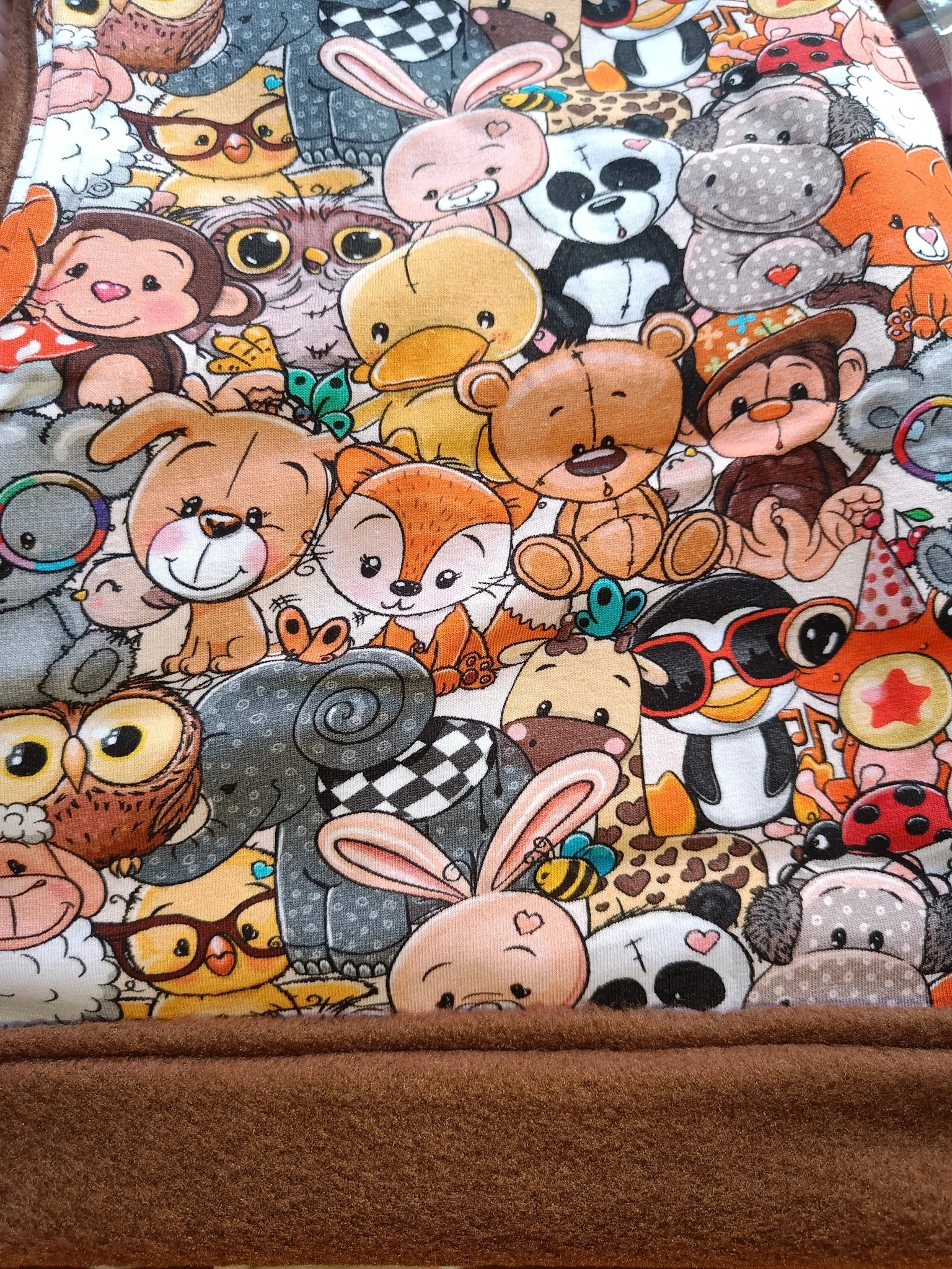 Primer plano de la tela del Buff'n'hood con ilustraciones de peluches: osos, pandas, conejos y otros animales adorables. [variant: Chocolate]