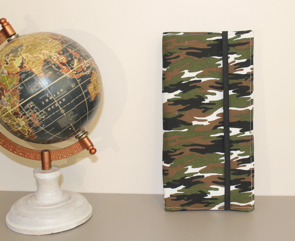 Kit dental infantil artesanal con estampado camuflaje verde cerrado, presentado sobre superficie beige junto a un globo terráqueo decorativo.