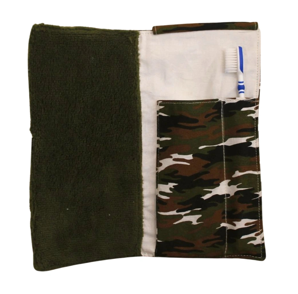 Kit dental infantil abierto con cepillo dentro del bolsillo de camuflaje verde y toalla de rizo verde, fondo blanco neutro.