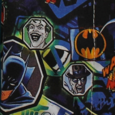 Detalle del estampado infantil de Batman con Joker, símbolo del murciélago y estética de cómic sobre fondo oscuro