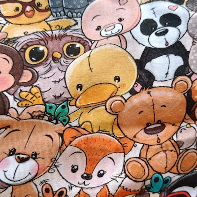Detalle cercano del estampado "Peluches", con personajes sonrientes y expresivos en tonos cálidos y anaranjados.