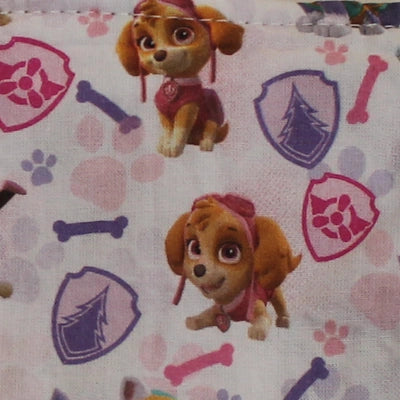 Detalle del estampado infantil con Skye de la Patrulla Canina, escudos, huesos y huellas en tonos rosas y lilas