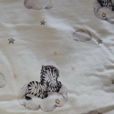 Detalle del estampado de cebritas dormidas sobre nubes con estrellitas en tonos suaves.